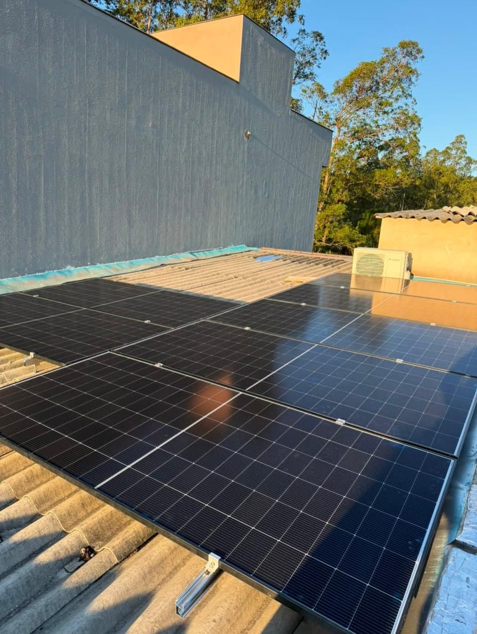 Módulos fotovoltaicos instalados em telhado de fibrocimento ao entardecer